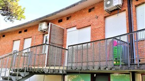 A multi-story building with a staircase leading to a balcony. There are air conditioning units on the exterior walls.