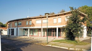 A two-story building with a flat roof, large windows, and a small entrance area.
