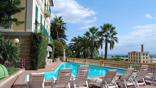A poolside area with lounge chairs, a pool, and a view of the sea. - Studio mit Pool (Imperia)