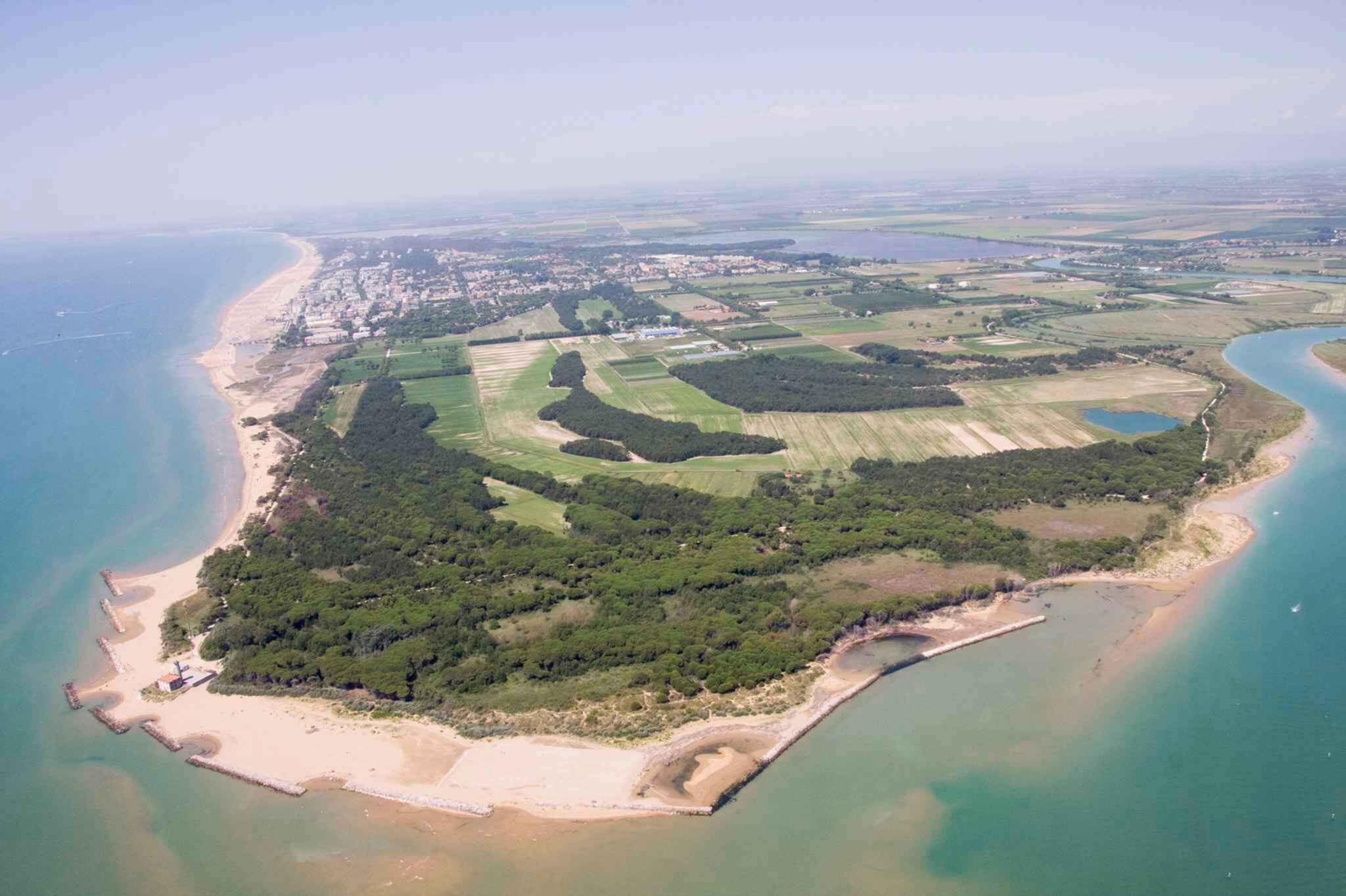 Vue aérienne d’une zone côtière avec une plage, des champs et un petit village.