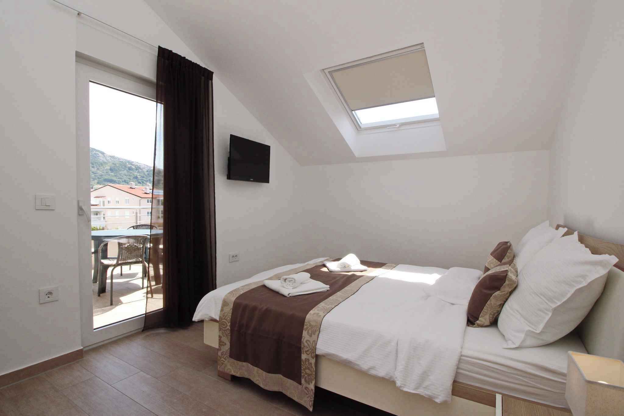 A bedroom with a bed, a TV, a skylight, and a view of the outside.