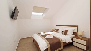 A bedroom with a bed, bedside tables, a TV mounted on the wall, and a skylight. - Holiday apartment with air conditioning and Wi-Fi (Baška)
