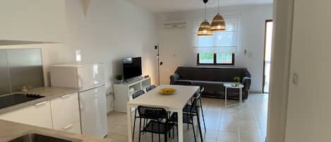 A compact kitchen with a dining area, a sofa, and a TV.