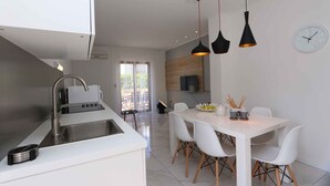 A modern kitchen with a built-in sink, white cabinetry, and pendant lighting.
