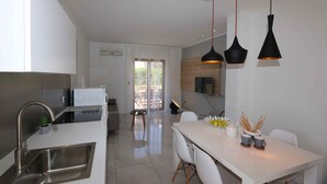 A modern kitchen with a built-in oven, a sink, and a dining area with a white table and chairs.