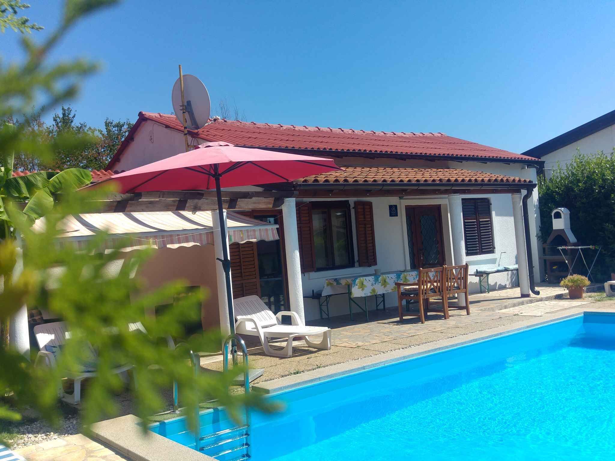 A two-story house with a swimming pool, a red umbrella, and a satellite dish.