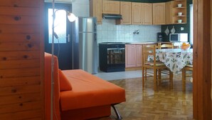 A compact kitchen with wooden cabinets, a refrigerator, a stove, and a microwave. - Holiday home with washing machine and smart TV (Valbandon)