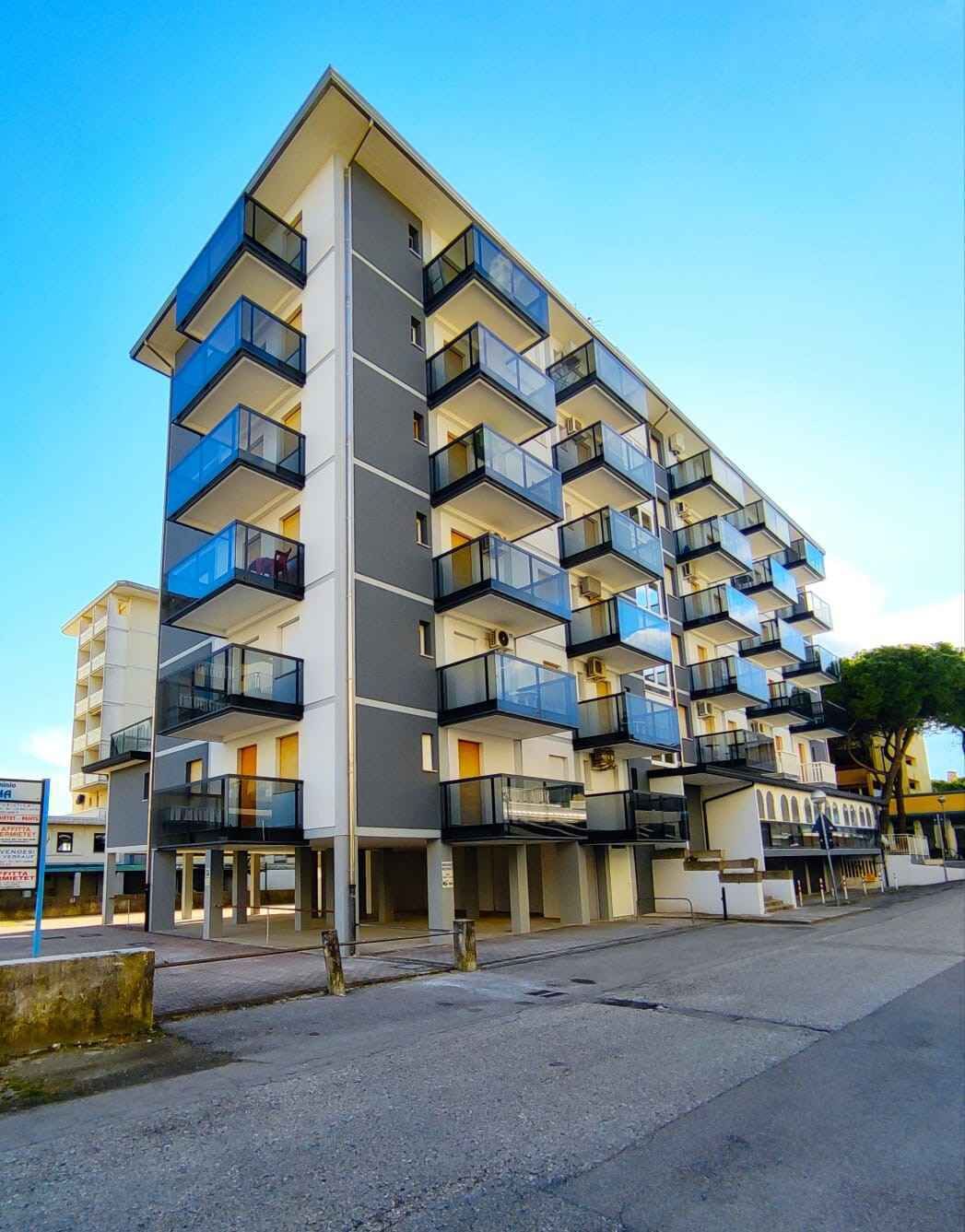 Un edificio de varios pisos con balcones, fachada plana y cielo despejado.