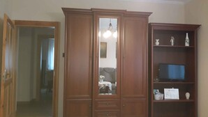 A room with a wooden wardrobe, a television on a shelf, and a mirror. - Holiday apartment with WiFi near the thermal baths (Hévíz)