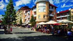 A courtyard with outdoor seating, a central building with balconies, and a clear blue sky. - Holiday apartment with WiFi near the thermal baths (Hévíz)