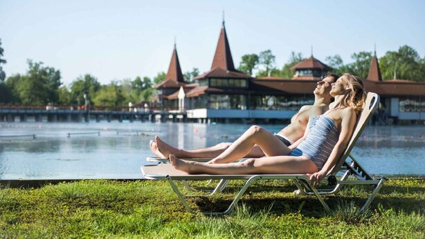 A couple relaxing by a pool with traditional architecture in the background. - Holiday apartment with WiFi near the thermal baths (Hévíz)