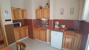 A compact kitchen with wooden cabinets, a microwave, a sink, a coffee maker, and a dishwasher. - Holiday apartment with WiFi near the thermal baths (Hévíz)