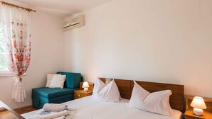 Ein Hotelzimmer mit einem Bett, einem kleinen Sofa, einem Nachttisch mit Lampe und einer Klimaanlage an der Wand.