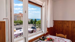Ein Balkon mit Esstisch, Obstschale und Blick auf Gebäude und Bäume.
