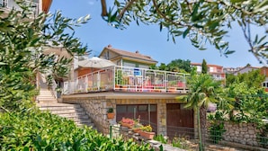 Ein Wohngebäude mit Balkon, Steintreppe und Topfpflanzen.