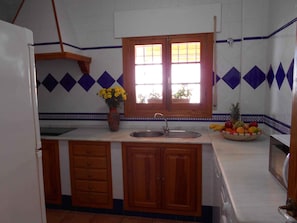 A kitchen with wooden cabinets, a sink, and a window with a view.