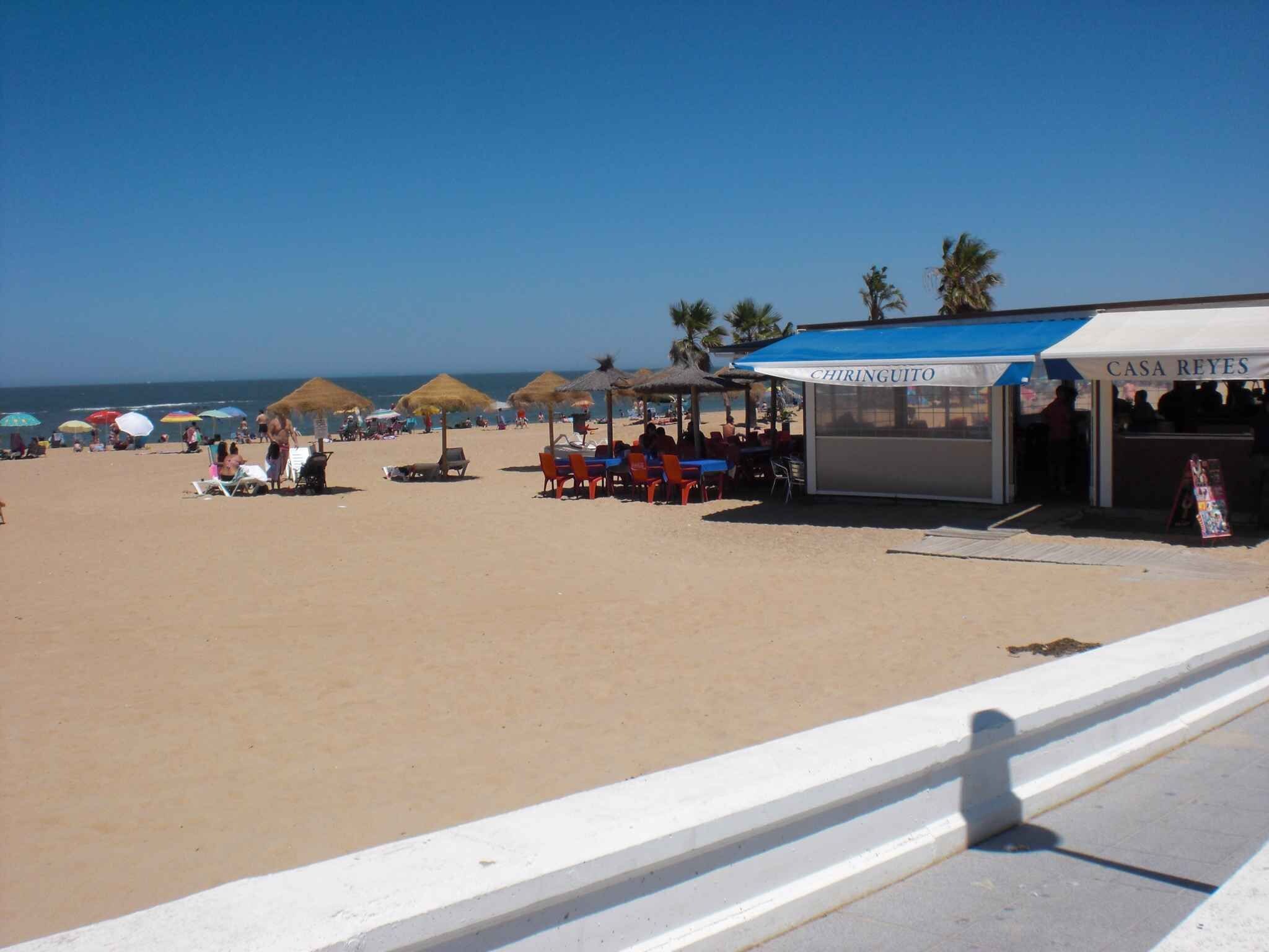 A beach with umbrellas, a restaurant named 'CHIRINGUITO,' and another named 'CASA REYES.'