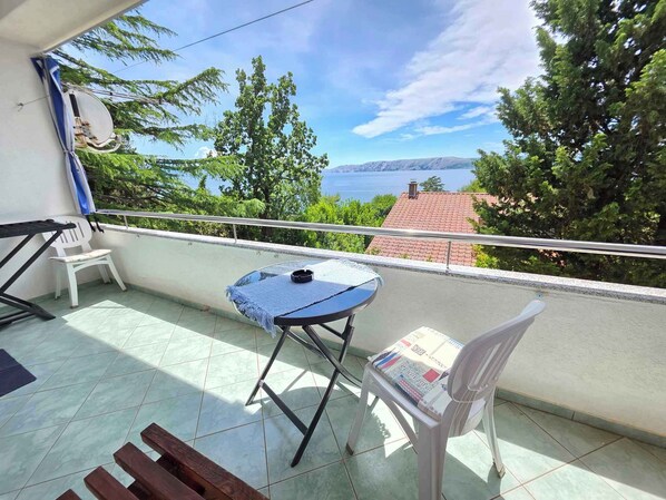 Un balcon avec une table, des chaises et une vue sur la mer.