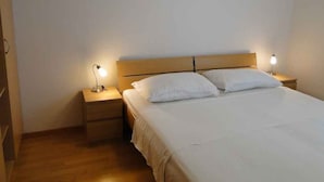 Ein Einzelbett mit weißer Bettwäsche, zwei Nachttische mit Lampen und ein Holz-Kopfteil.
