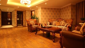 A spacious living room with a wooden floor, a large sofa, two armchairs, a coffee table, and a chandelier. - Jiali Holiday Inn Wanhe Branch (Chengdu)
