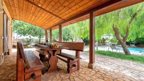An outdoor patio with a wooden table, benches, and a stone floor. - Villa with air conditioning (Campanedda/Sassari)