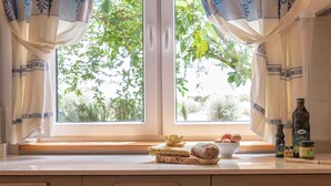 A kitchen with a window, a bowl of eggs, a loaf of bread, and condiments on the counter. - Villa with air conditioning (Campanedda/Sassari)