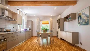 A modern kitchen with wooden flooring, a dining area with a table and chairs, and built-in cabinets. - Villa with air conditioning (Campanedda/Sassari)