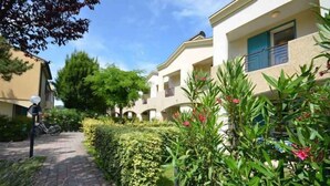 A residential building with a paved pathway, greenery, and a bicycle. - Holiday apartment with air conditioning and terrace (Bibione)