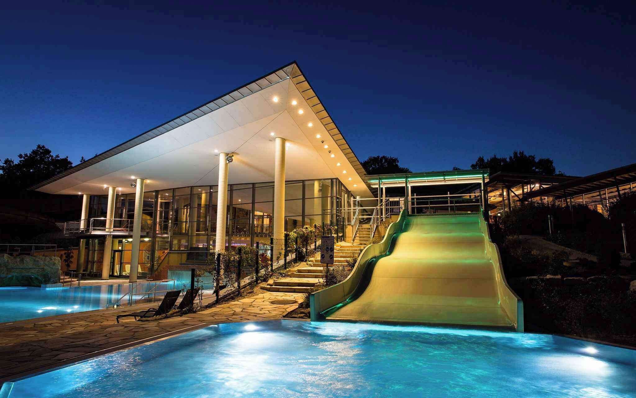 Ein modernes Gebäude mit Glasfassade, Pool und Wasserrutsche.
