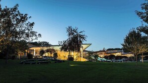 A modern building with a glass facade, surrounded by a grassy area and trees. - Holiday apartment at the Therme Obernsees (Mistelgau-Obernsees)
