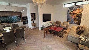 Uma sala de estar moderna com televisão, sofá e área de jantar.