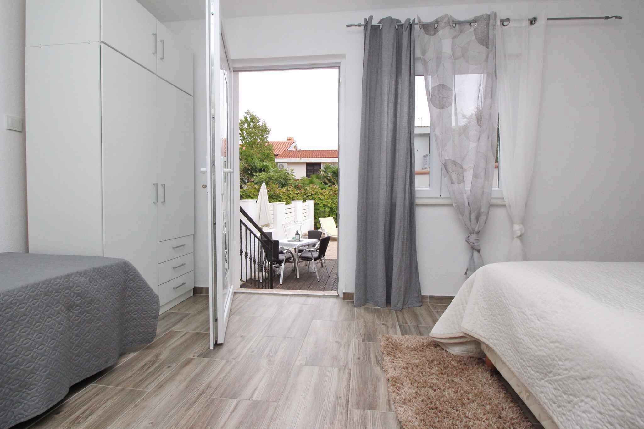 A bedroom with a bed, a wardrobe, and a view of an outdoor patio area.