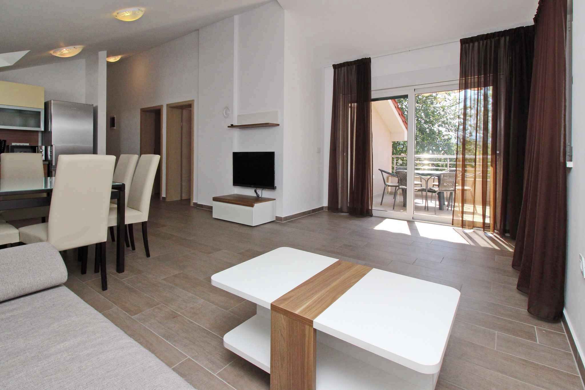 A modern living room with a sofa, a dining table, a TV, and a balcony with curtains.