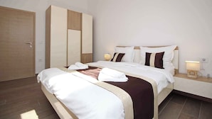 Une chambre d’hôtel moderne avec un grand lit, une armoire, une table de chevet avec une lampe et une petite table de nuit.