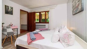 A bedroom with two beds, a desk, and a chair.