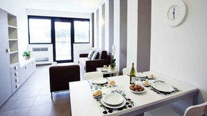 A modern dining area with a table set for two, a bottle of wine, and a bowl of nuts.