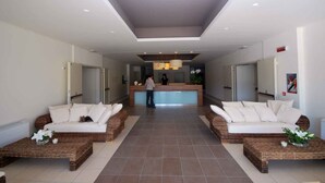 A hotel lobby with a reception desk, two sofas, and a person standing at the desk.