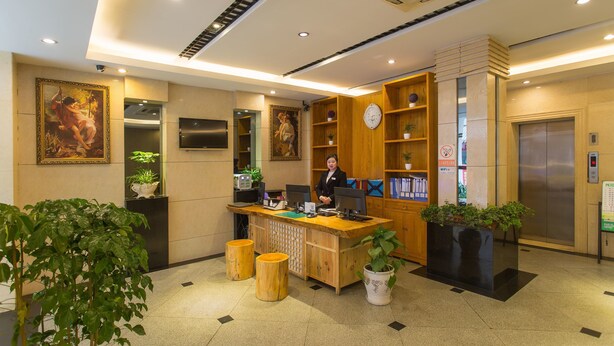 A reception desk with a receptionist, a clock, and a plant.