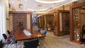 A conference room with a wooden table, black chairs, and patterned carpet.