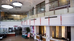 A spacious lobby with a reception desk, a staircase, and a glass railing.