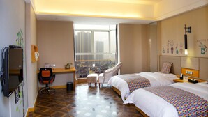 A hotel room with a large window, a desk, two beds, and a chair.