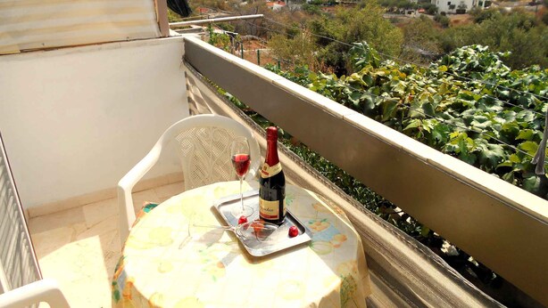Un balcón con una mesa, una botella de vino y una copa en una bandeja.