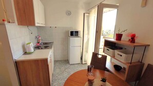 Una cocina compacta equipada con microondas, refrigerador y un comedor con mesa y sillas.