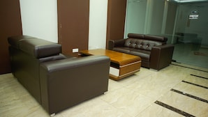 A seating area with a sofa and armchair, a wooden coffee table, and a tiled floor. - Bitz Hotel (Kuala Lumpur)