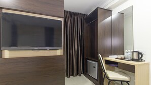 A compact room with a TV, a small fridge, a desk with a chair, and a mirror. - Bitz Hotel (Kuala Lumpur)