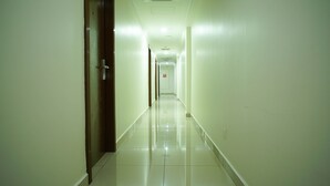 A long, narrow hallway with a shiny tiled floor and white walls. - Bitz Hotel (Kuala Lumpur)
