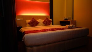 A hotel room with a large bed, two pillows, a red throw, and a nightstand with a lamp and a bottle. - Bitz Hotel (Kuala Lumpur)