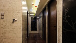 A hallway with tiled walls and a dark wooden door with a tree design. - Cindy Hostel (Kowloon)