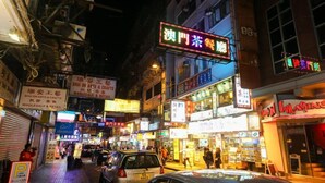 A busy street at night with various shops and signs, including one for 'Shun Arts & Crafts' and another for 'Wholesale & Retail'. - Cindy Hostel (Kowloon)