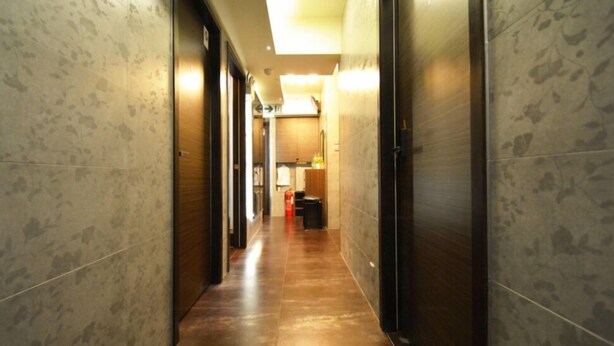 A corridor with marble walls and wooden flooring, leading to a room with a bed and a nightstand. - Cindy Hostel (Kowloon)